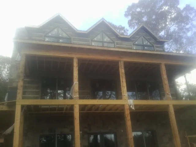 Dormers and porch framing on a large log home under construction — Roof Coating work by our crew in West Friendship
