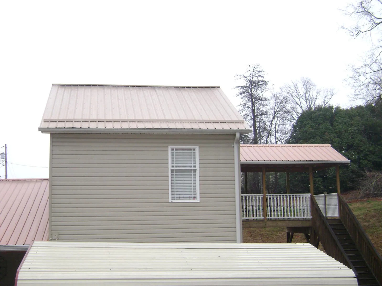 Tan metal roofs on a two story addition and attached porch, from a Roof Replacement job in West Friendship