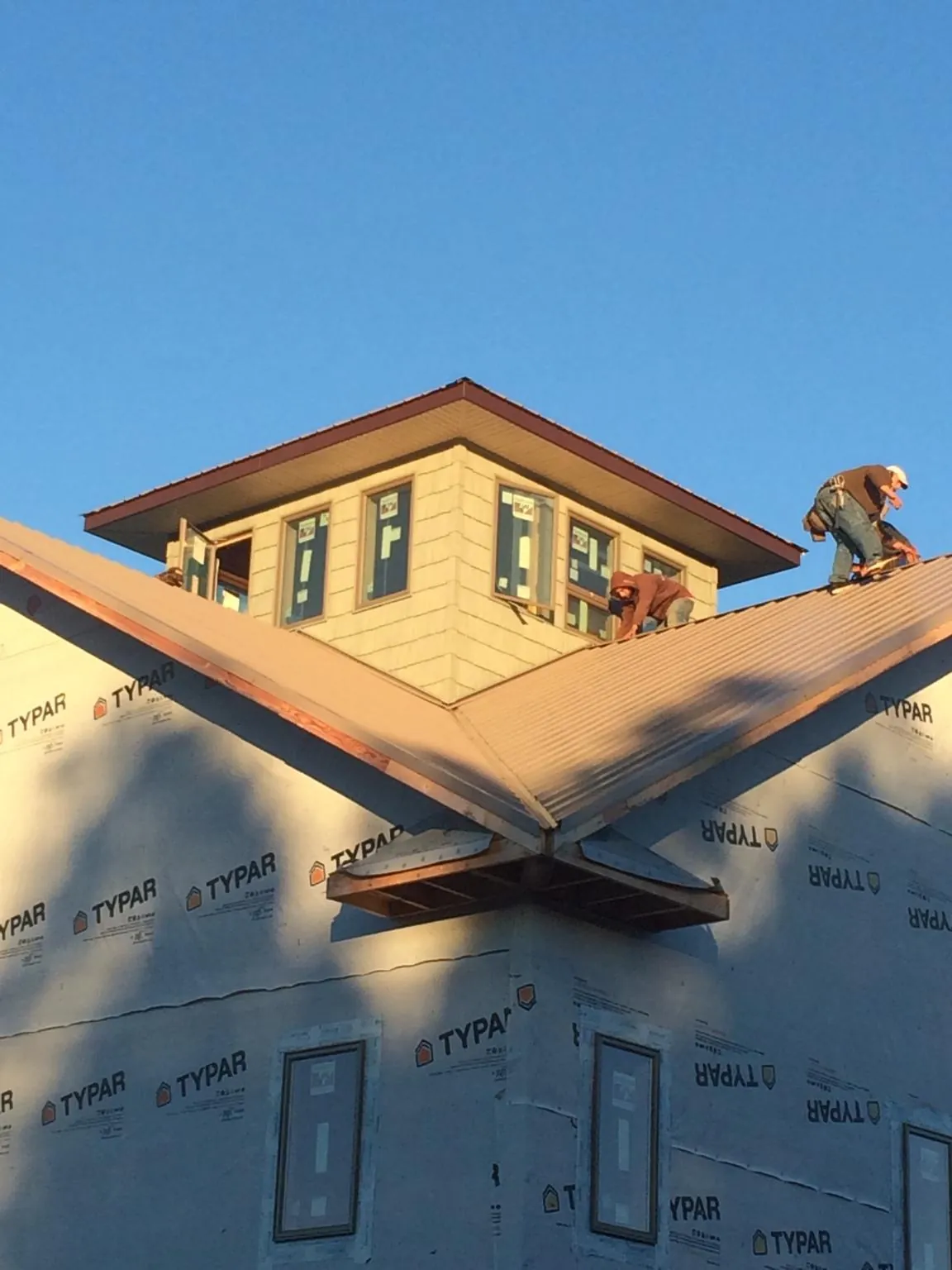 Roofers working around a rooftop cupola on a new metal roof at sunset — Roof Waterproofing in West Friendship by Roofing Brothers